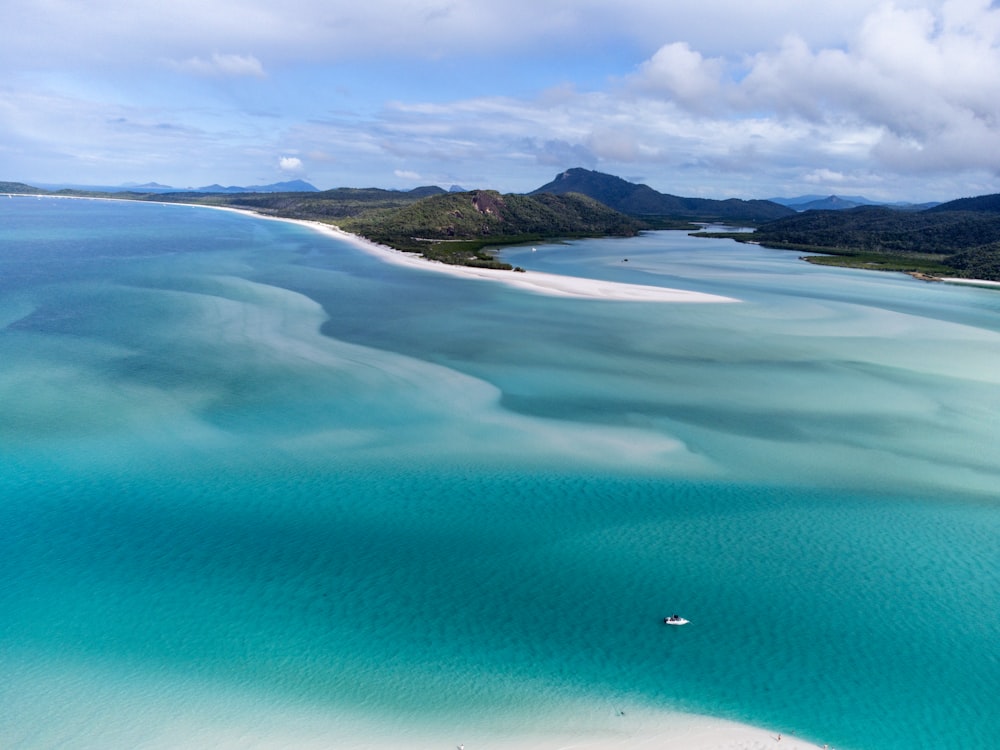 an aerial view of a beach with a boat in the water