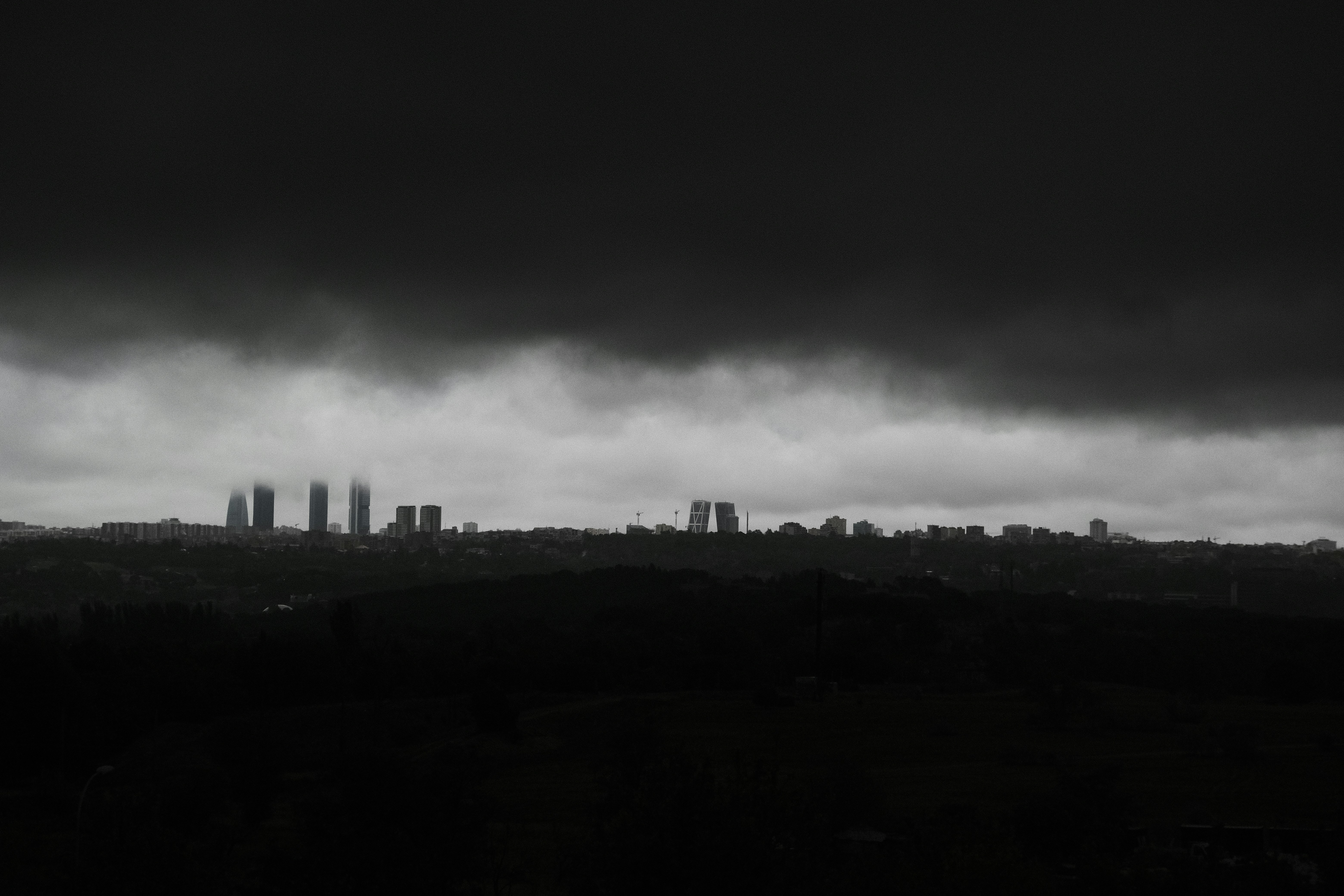 a black and white photo of a city under a cloudy sky, Madrid days