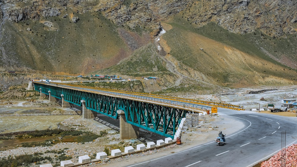 a motorcyclist rides across a bridge in the mountains