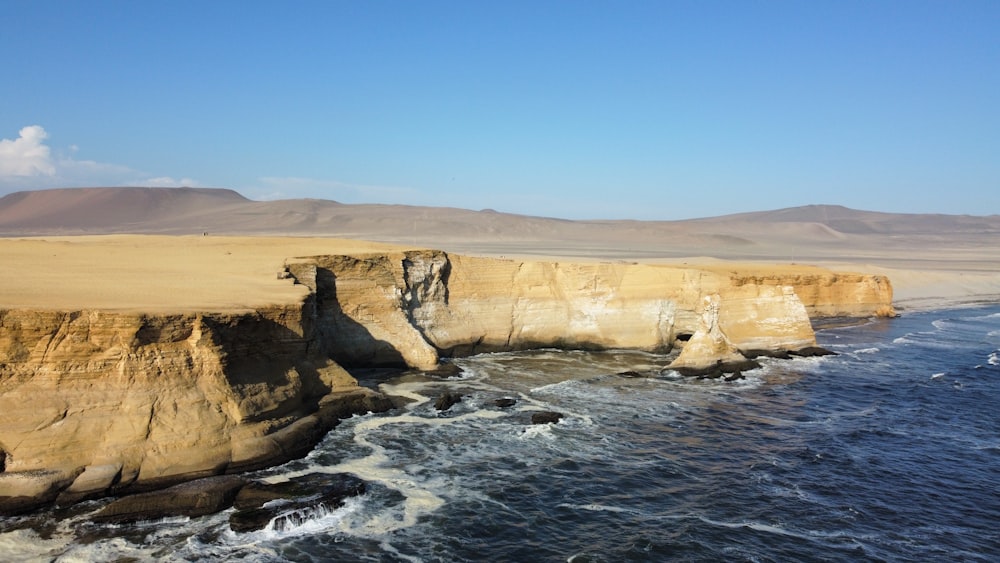 a large body of water next to a rocky cliff