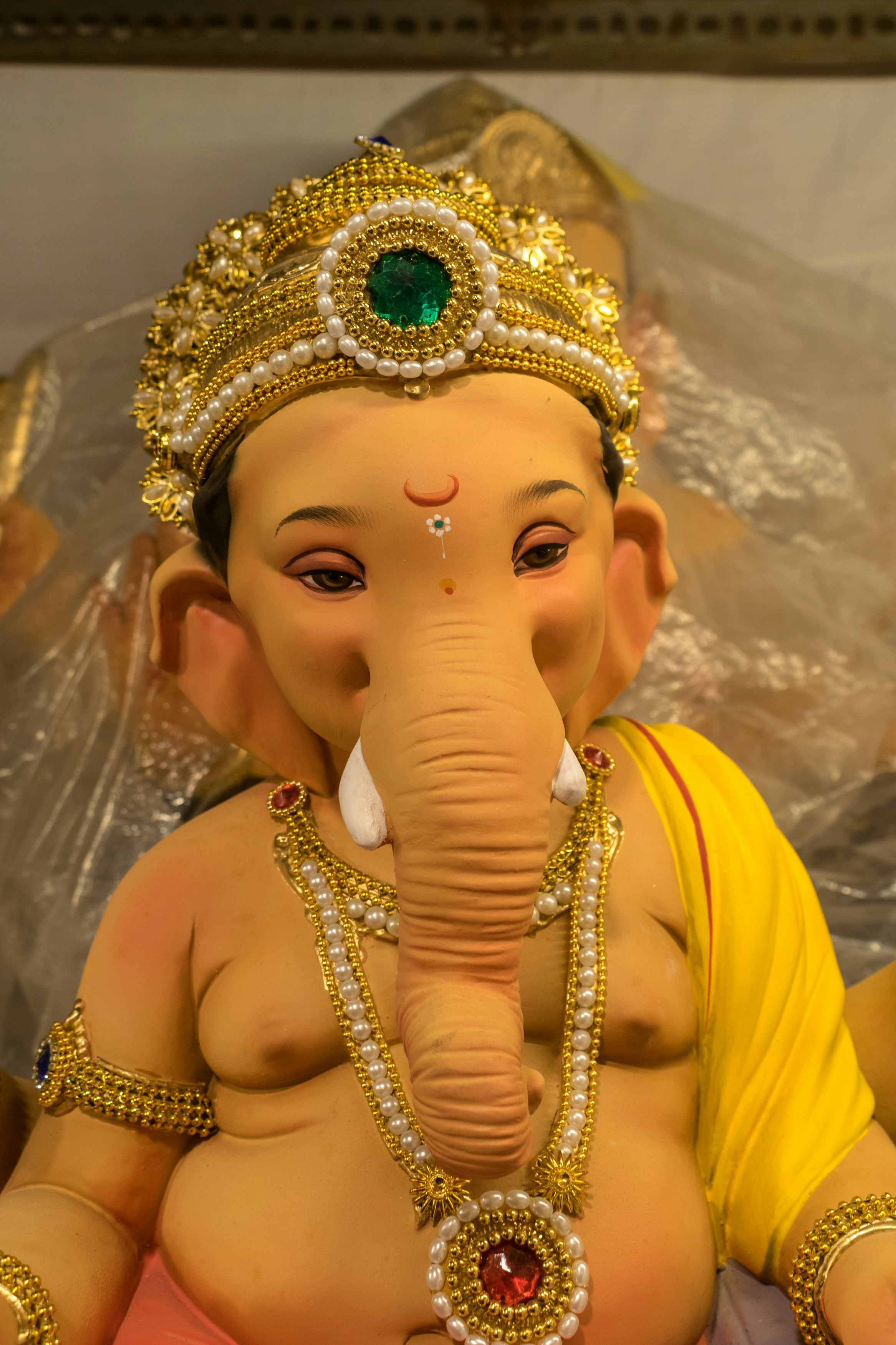 a statue of an elephant with a green jewel in its trunk