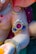 A close-up of a decorative sculpture featuring intricate jewelry designs. The sculpture has a glossy finish with embellishments of pearls and brightly colored stones, including red and blue gemstones. The jewelry includes ornate arm bands and necklaces with gold accents.