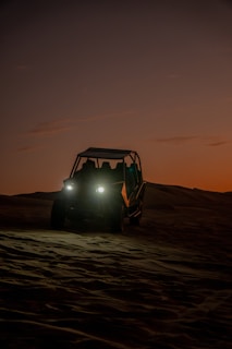 Sunset over the sand dunes of Huacachina with tourists riding dune buggies.