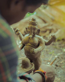 Artisan hands carefully molding eco-friendly clay into a Ganpati idol, highlighting craftsmanship.