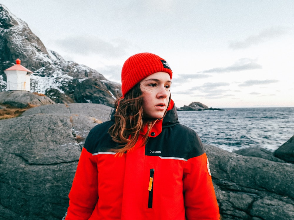 a woman standing on a rocky beach next to the ocean