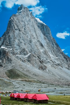 Technician setting up geophysical equipment against a vast mountainous landscape under a clear blue sky.