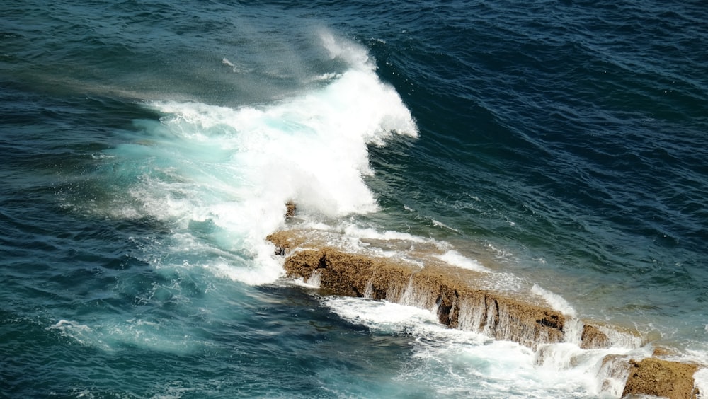 a large wave crashes into the rocks in the ocean