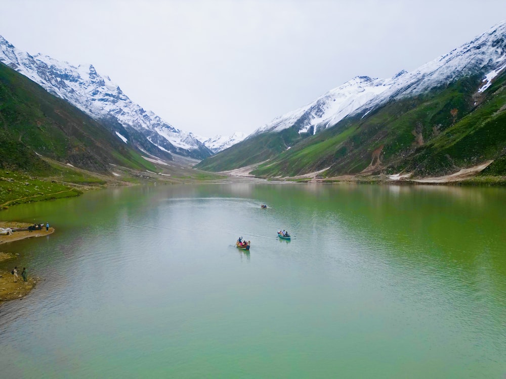 a group of boats floating on top of a lake surrounded by mountains