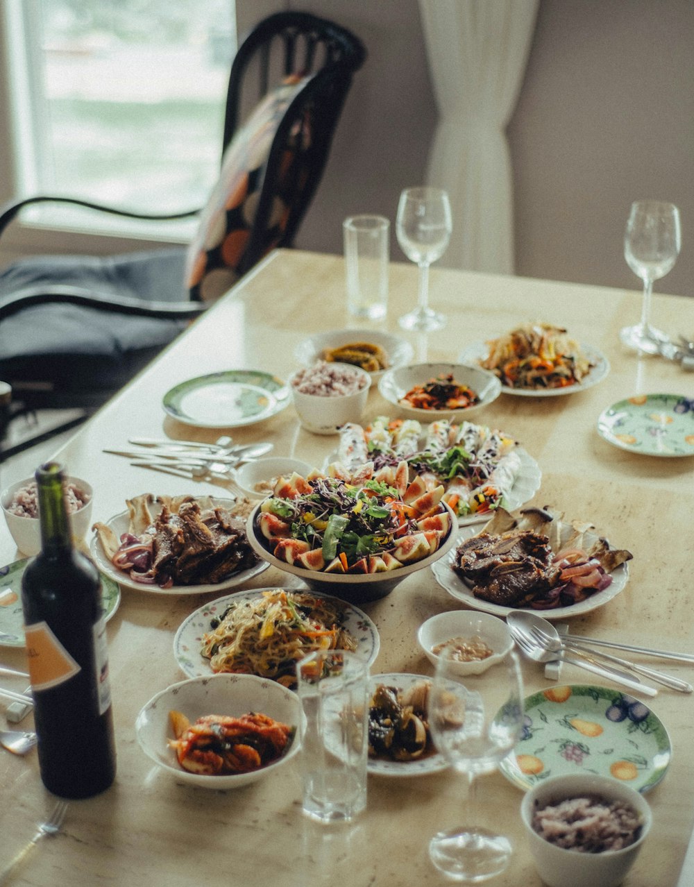 a wooden table topped with lots of plates and bowls of food