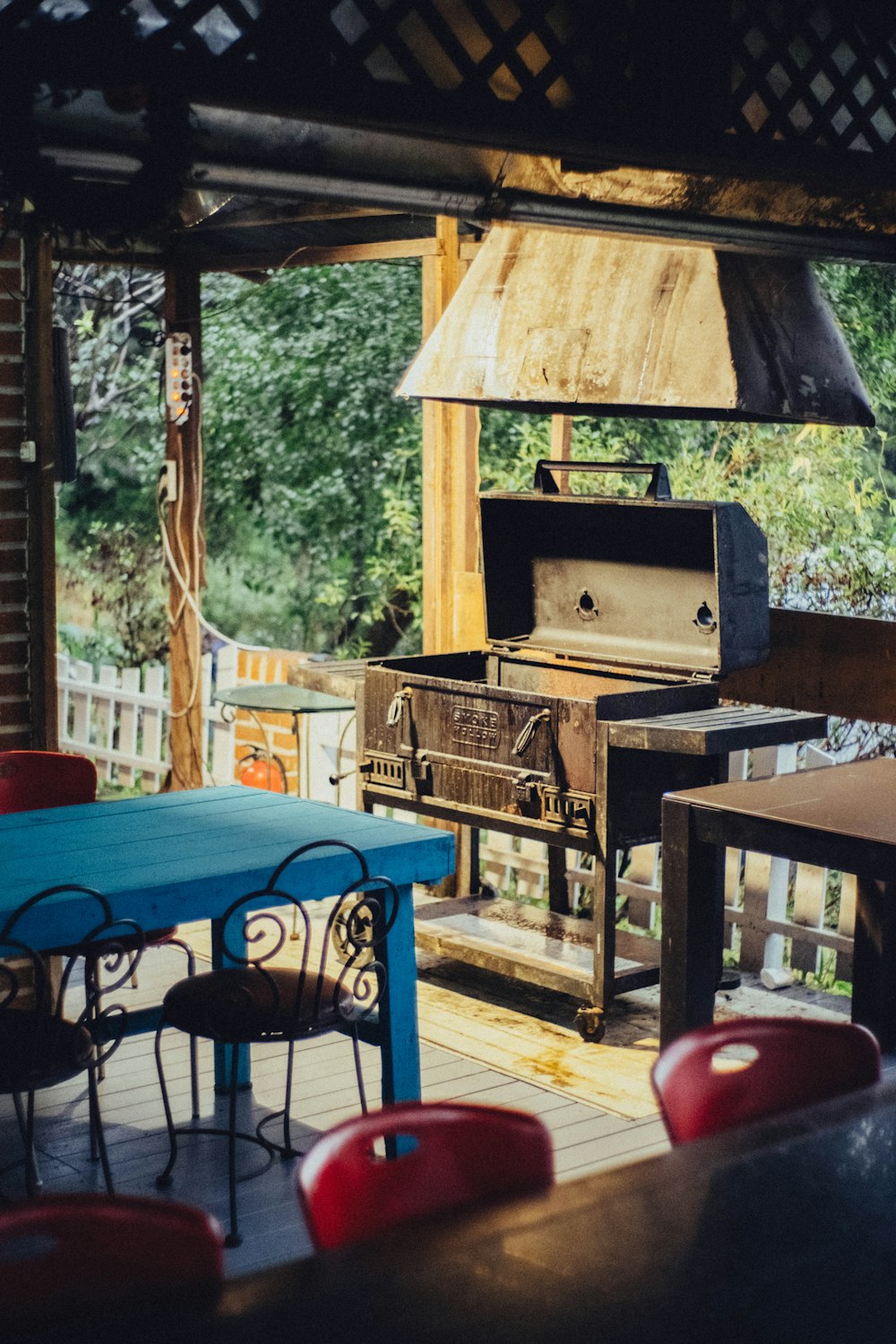 a patio with a blue table and red chairs