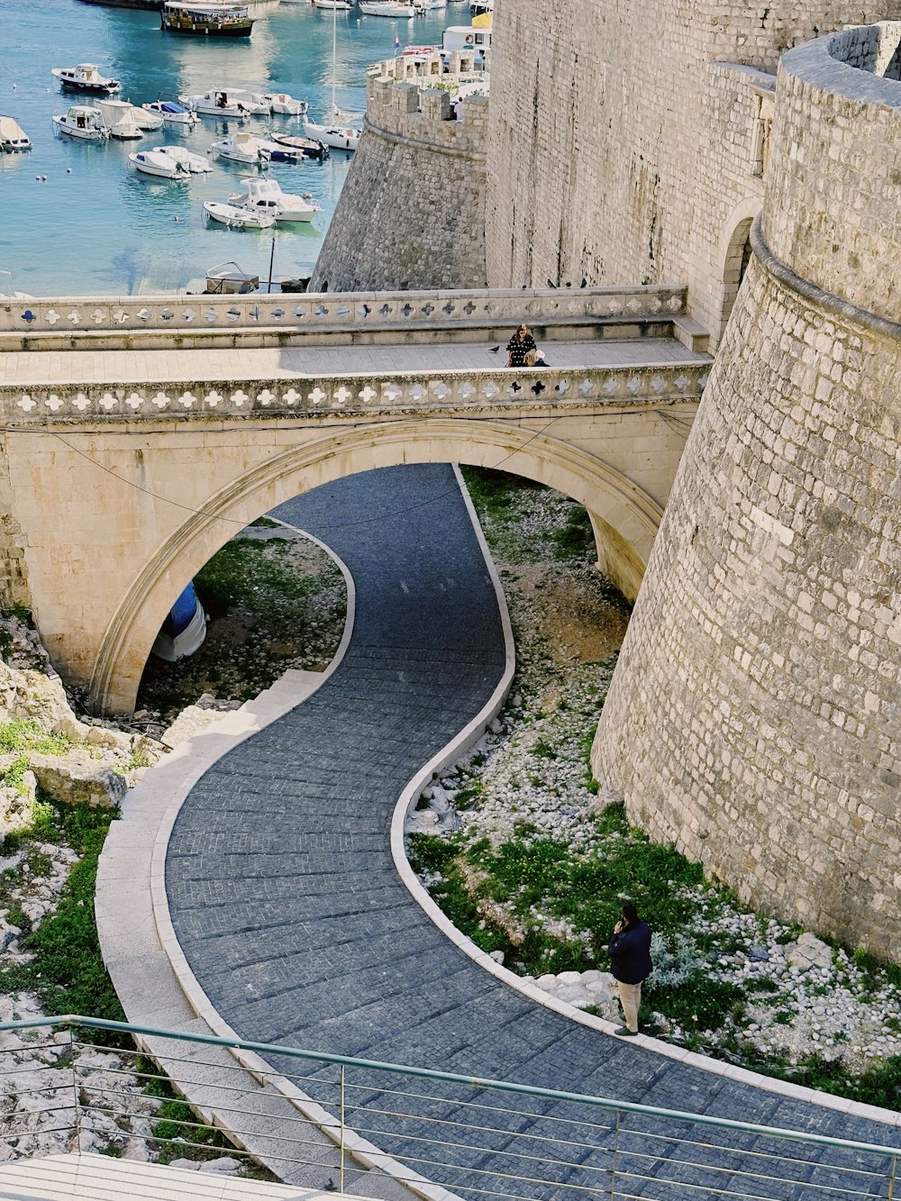 a person walking down a stone path next to a bridge