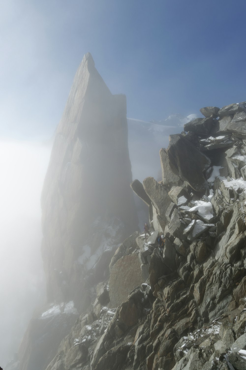 a rocky mountain covered in snow and fog