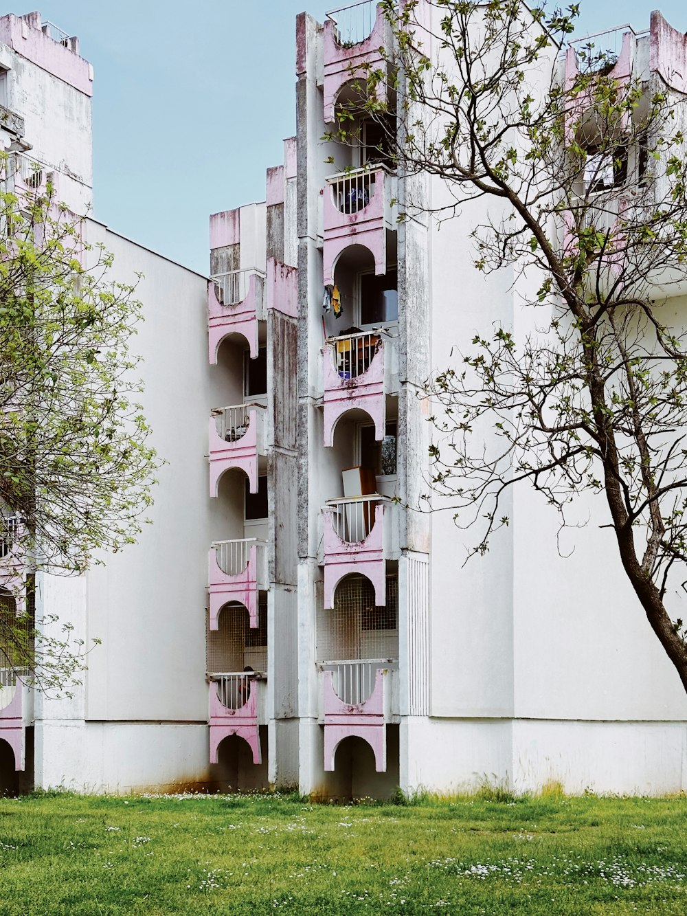 Un edificio alto y blanco con balcones rosados