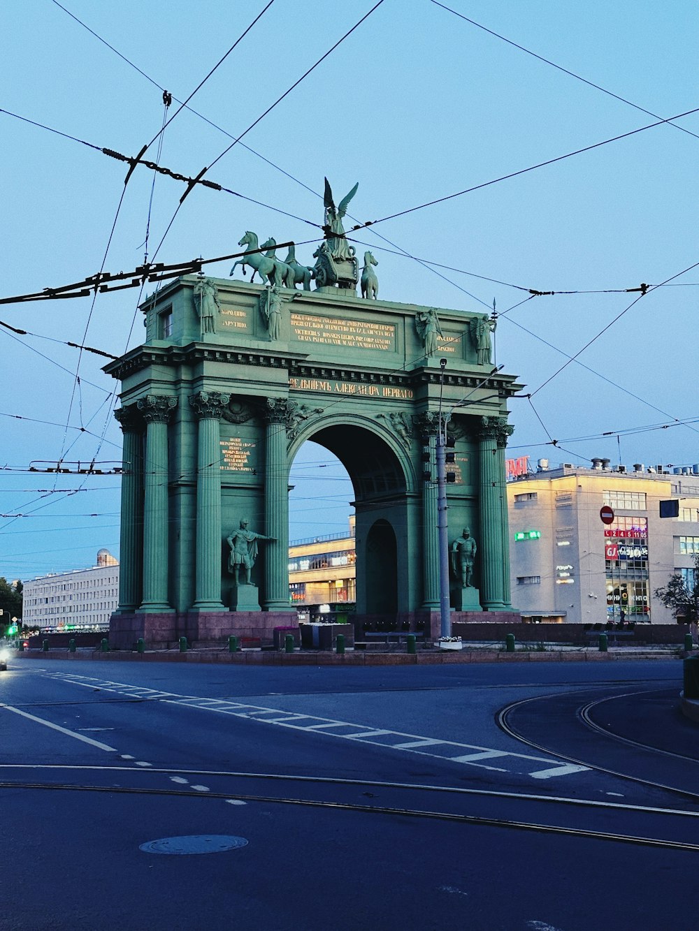 a large green arch with statues on top of it