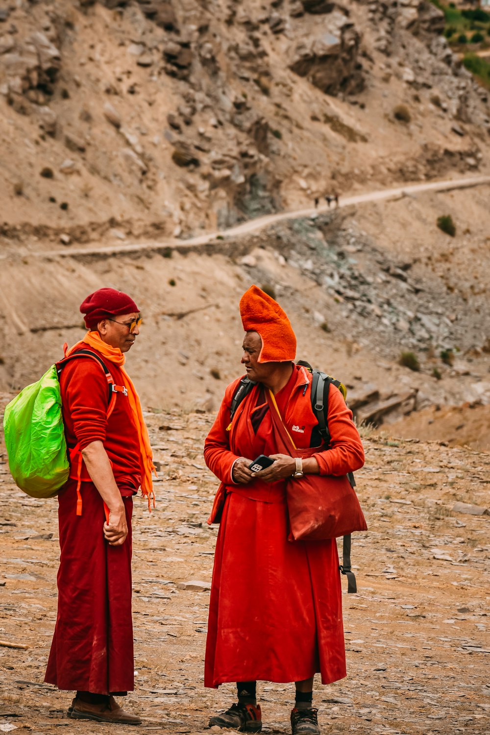 Dos hombres vestidos de rojo y naranja parados uno al lado del otro