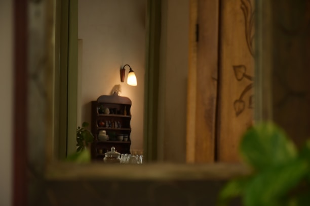 A person fixing a wooden shelf on a wall inside a cozy, warmly lit room.