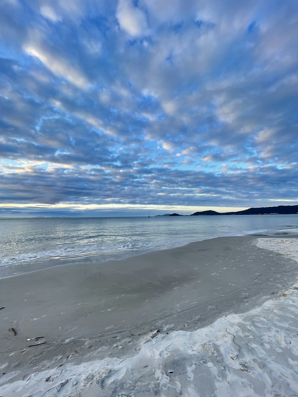 a beach covered in snow under a cloudy sky