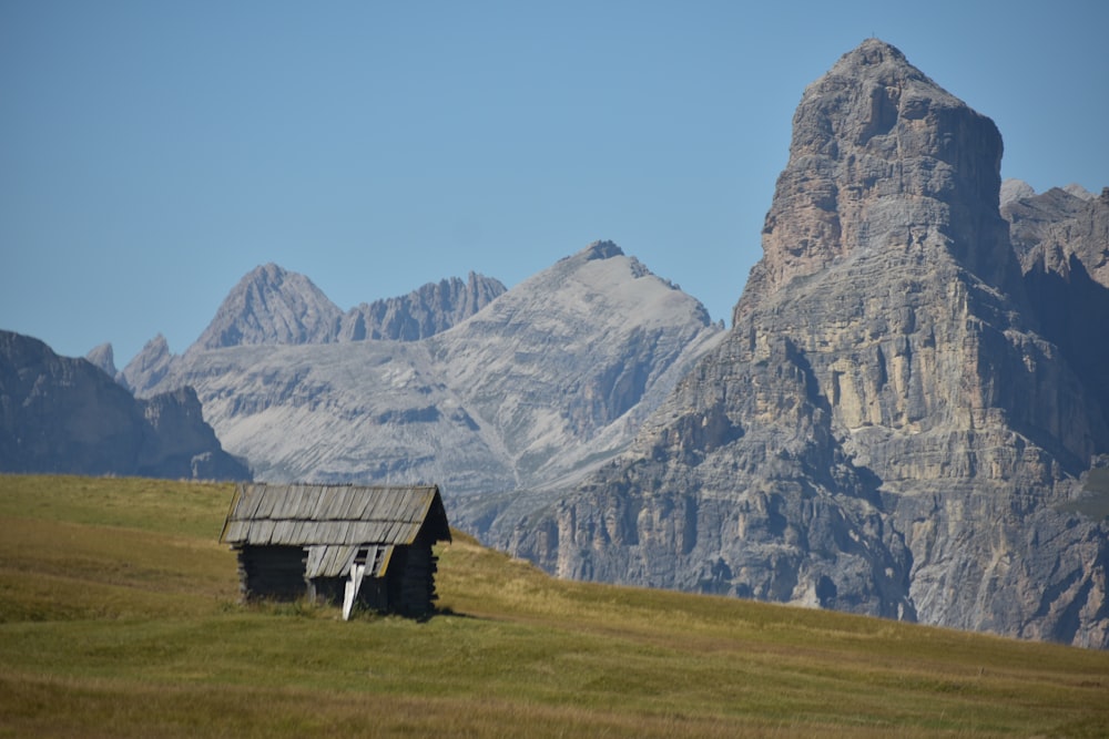 a cabin in a field with mountains in the background