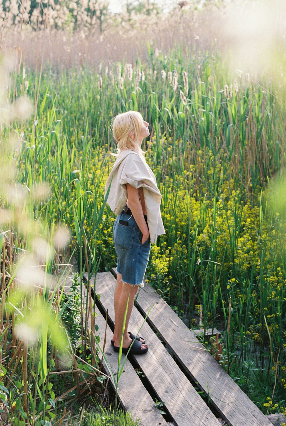 a little girl standing on a wooden bridge in a field