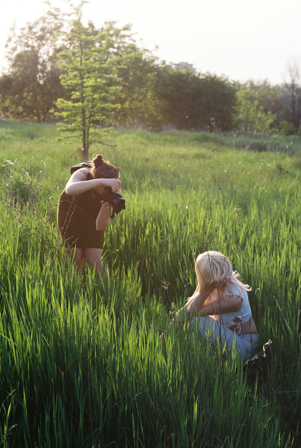 a woman taking a picture of another woman in a field