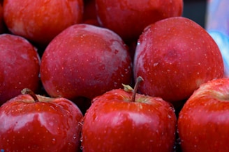 Close-up of juicy red apples with morning dew, highlighting their freshness and quality.
