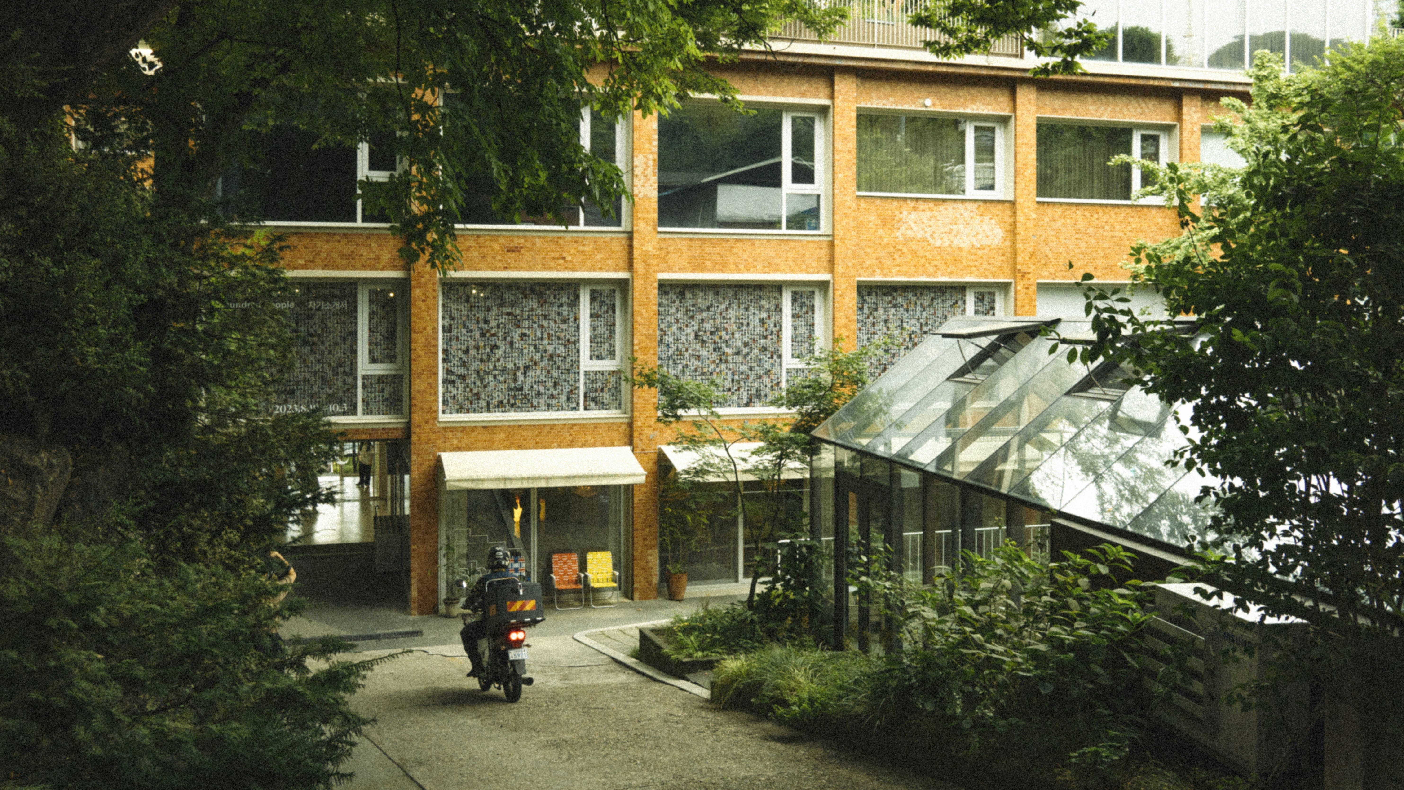 a man riding a motorcycle down a street next to a tall building
