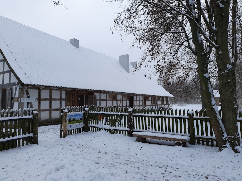 a house covered in snow next to a tree