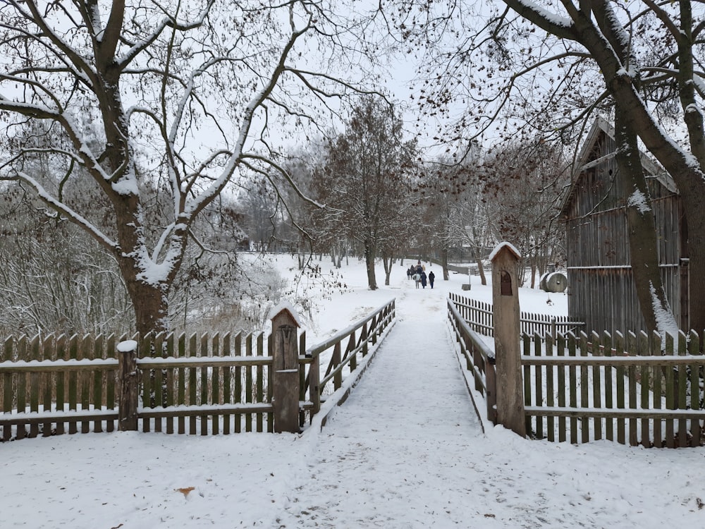 a snow covered path leading to a wooden fence