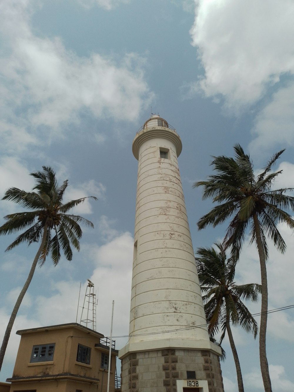 a white light house surrounded by palm trees