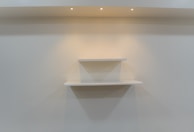 A professional installing shelves in a bright living room.