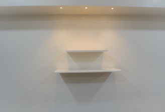 A professional installing shelves in a bright living room.