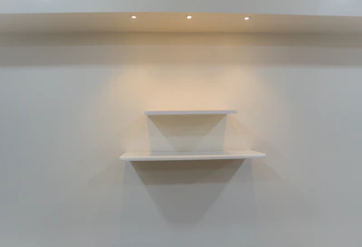 A sleek floating wooden shelf mounted on a soft beige wall with natural light highlighting the wood grain.