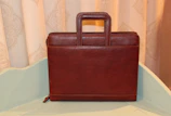 A sleek leather briefcase resting on a polished wooden desk in soft natural light.
