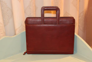 A sleek leather briefcase resting on a polished wooden desk in soft natural light.