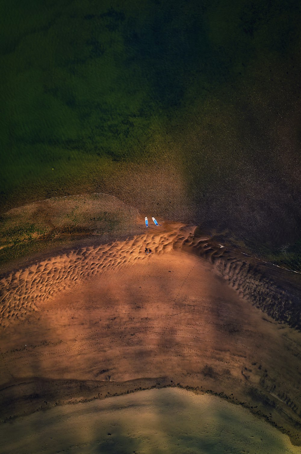 a couple of people walking across a dirt field