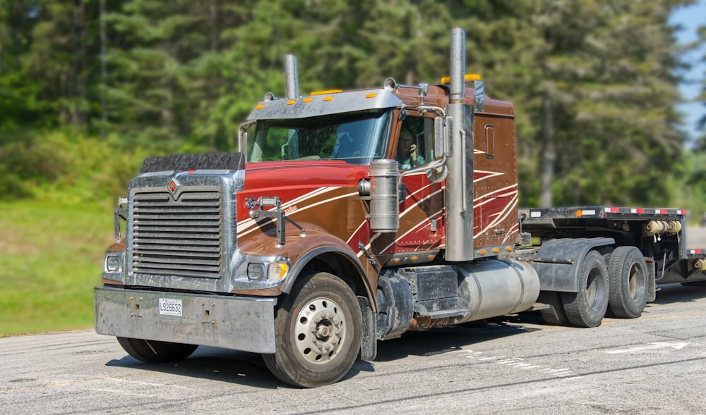 a red and brown semi truck driving down a road