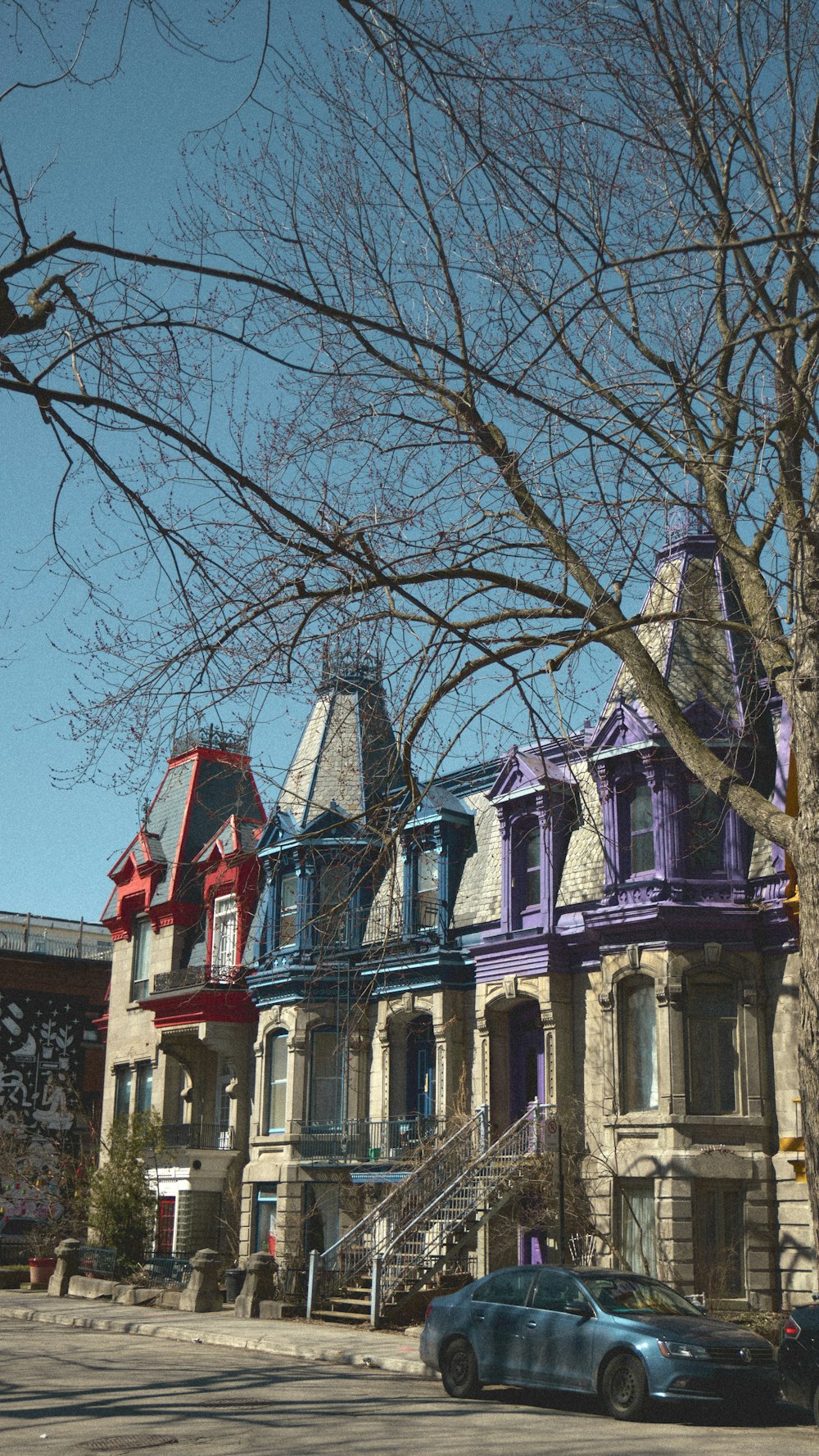 a blue car parked in front of a row of multi - colored houses