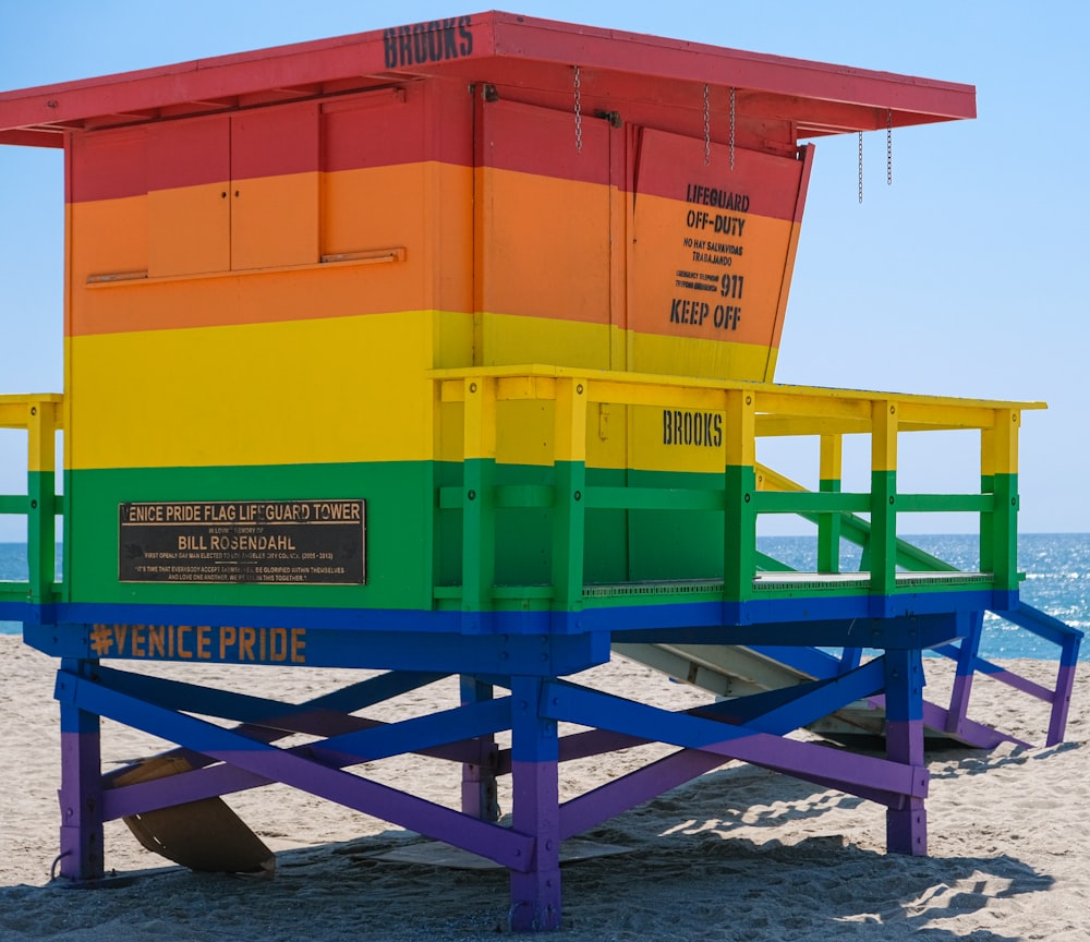 a colorful lifeguard tower on the beach with the ocean in the background