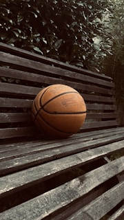 Close-up of colorful basketball wristbands stacked on a wooden bench outdoors