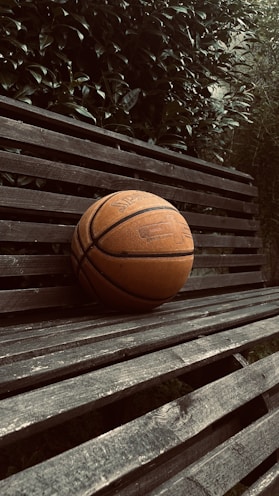 Elbow pads resting on a wooden bench with a sports field in the background.