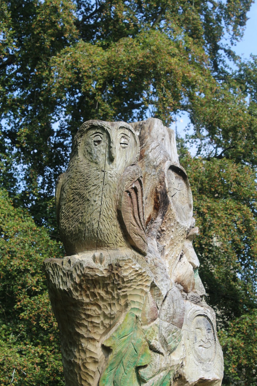 a statue of an owl with a tree in the background