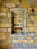 Close-up of textured natural stone walls blending seamlessly with the sand and off-white tones of the complex.