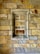 An intricate pattern of interlocking stone blocks in varying shades of beige, tan, and gray forms a textured wall. A recessed section, bordered by a stone frame, is seamlessly integrated into the stonework.