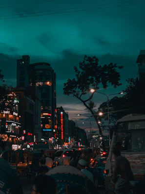 Bustling street scene in Dhaka with lively vendors and historic architecture glowing at dusk.