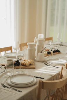 a table set for a formal dinner with wine glasses and plates