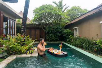 Traveler relaxing by a hotel pool with a tropical drink, enjoying a trip planned by viajeconfiable.