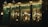 Warm ambient lighting illuminates an inviting cafe interior, visible through large glass windows. The facade features ornate details and vintage decor, with string lights adding a cozy charm. Inside, patrons engage in quiet conversation, surrounded by an eclectic mix of furniture and wall hangings.