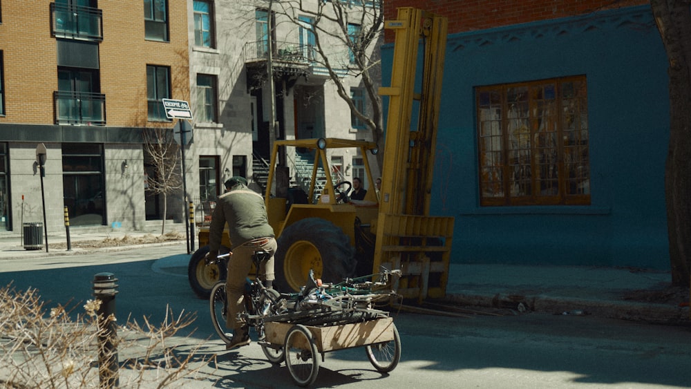 a man riding a bike down a street next to a fork lift