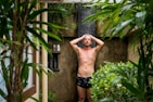 Relaxed person enjoying a natural body wash under a warm shower.