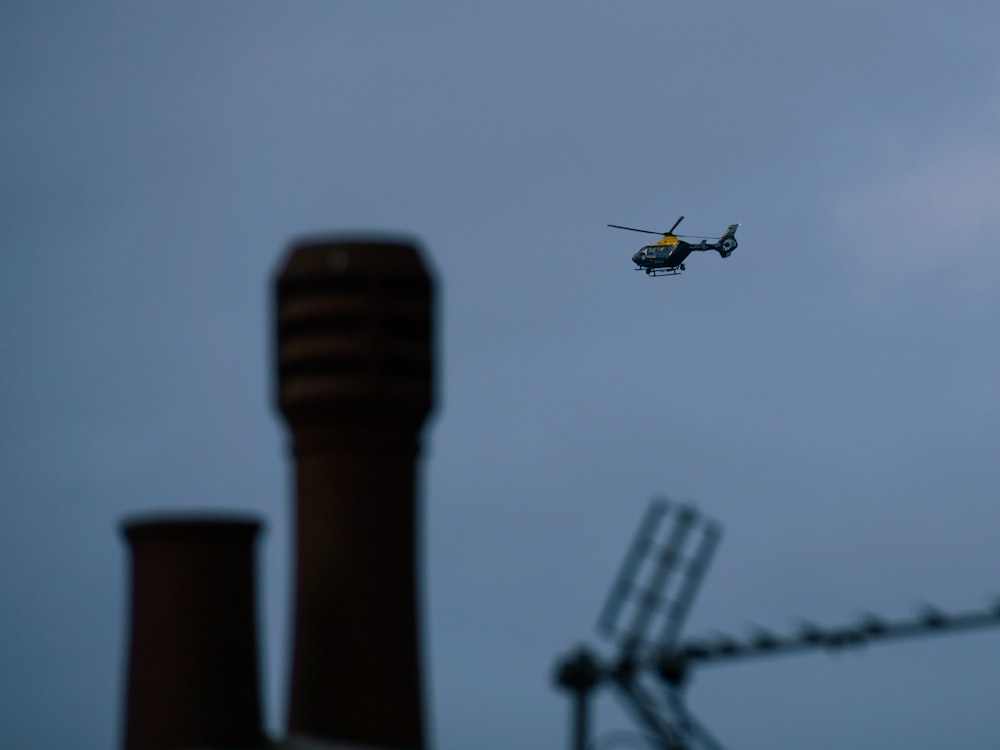 a helicopter flying over a factory with smoke stacks